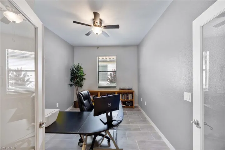 Office featuring ceiling fan, a textured wall, and french doors