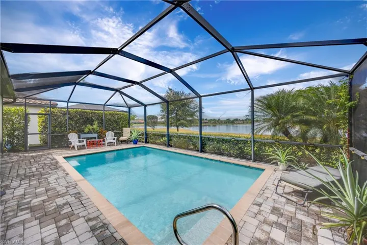 Outdoor pool featuring a sunroom, a water view, glass enclosure, and a patio