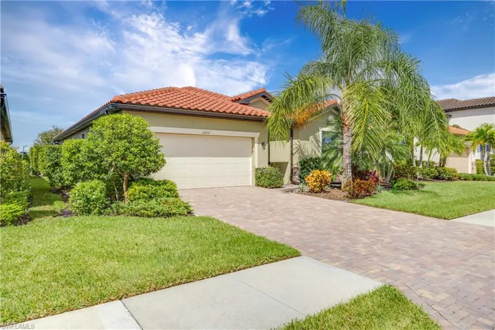 A beautiful home featuring a front lawn, stucco siding, decorative driveway, and a tile roof