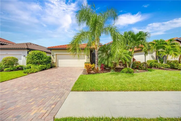 A beautiful home with a front lawn, decorative driveway, stucco siding, a garage, and a tile roof