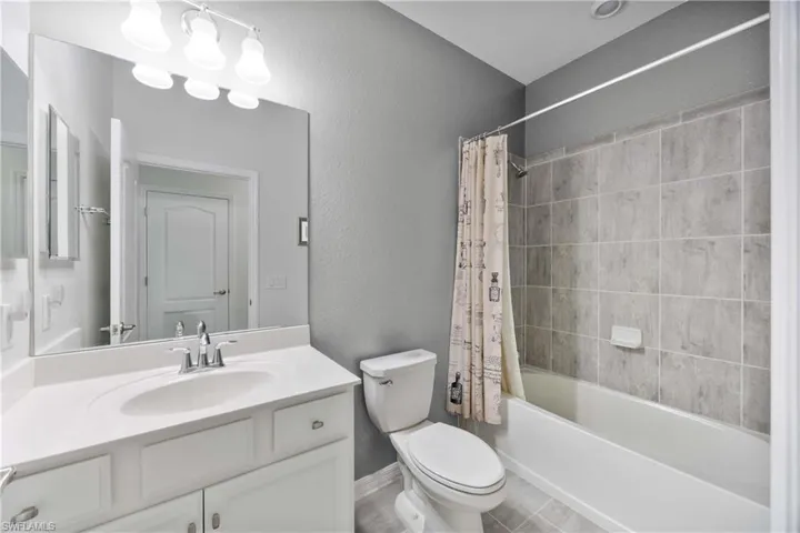 Full bath featuring shower / bath combo with shower curtain, vanity, and a textured wall