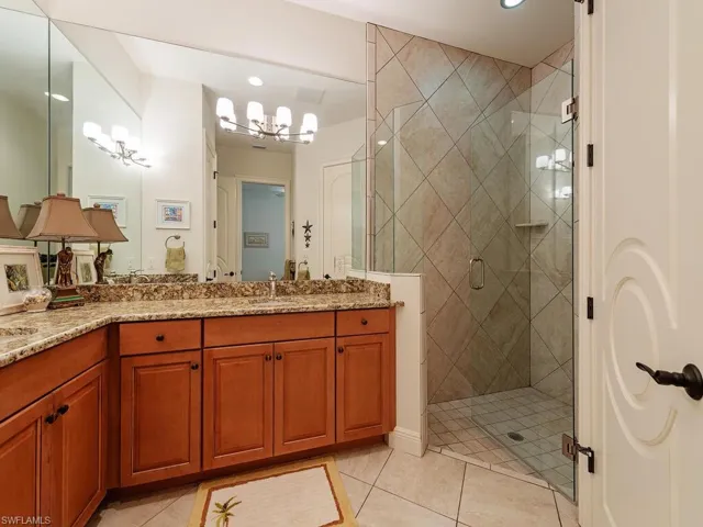 Bathroom featuring tile patterned floors, vanity, a notable chandelier, and a stall shower