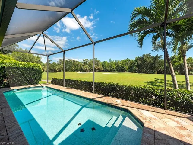 Pool featuring a lawn, glass enclosure, and view of golf course