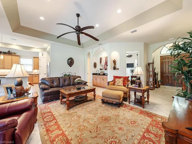 Living area with light tile patterned floors, ceiling fan, arched walkways, visible vents, and recessed lighting