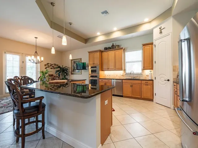Kitchen featuring stainless steel appliances, a sink, visible vents, a kitchen bar, and light tile patterned floors
