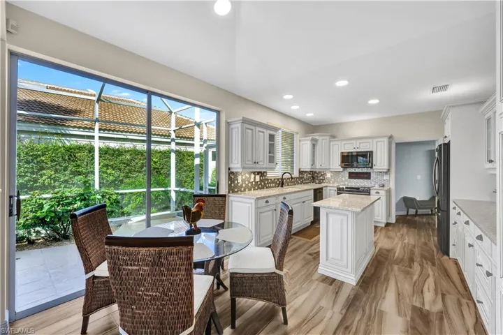 The classic Florida kitchen with white cabinetry, an island for food prep, and a bright, sunny breakfast area.