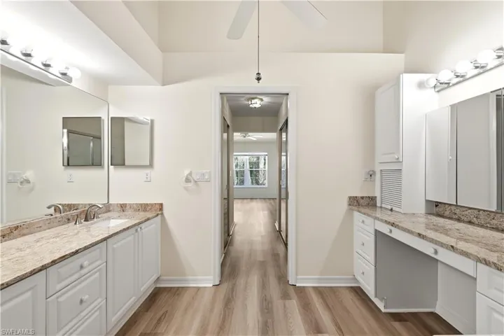 Spacious bathroom featuring dual vanities with stone countertops and white cabinetry