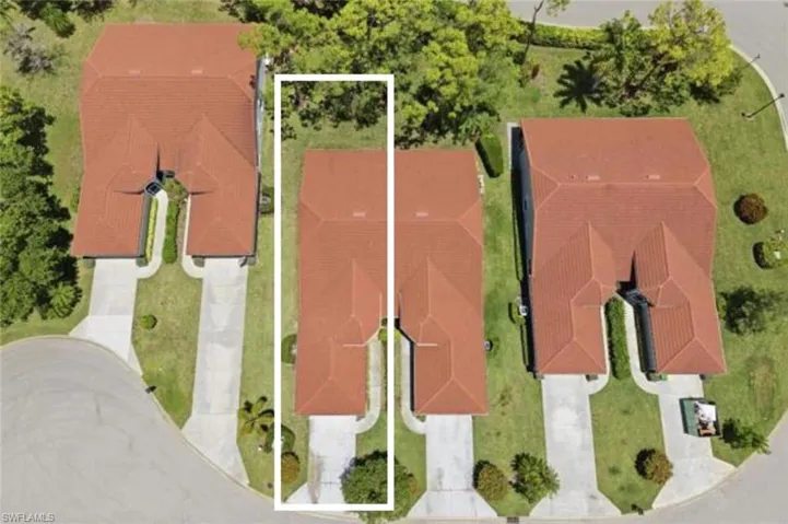 Residential property featuring a terracotta tile roof, a light-colored driveway, and green landscaping