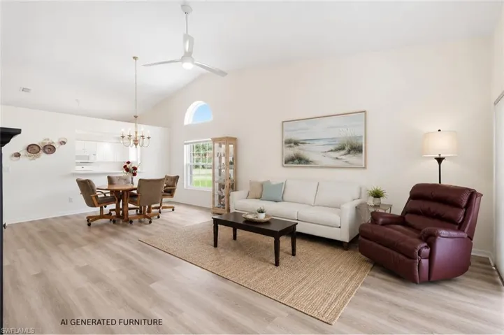 Vaulted ceiling living area featuring wood-finish flooring, a contemporary ceiling fan, and an arched transom window