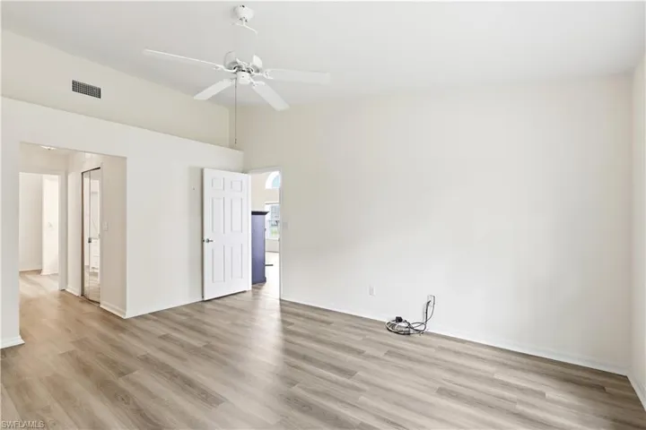 Spacious room featuring vaulted ceilings, a ceiling fan, and light wood-finish flooring