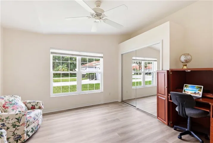 Vaulted ceiling room featuring light-toned wood-finish flooring, a ceiling fan, and a large window with white blinds