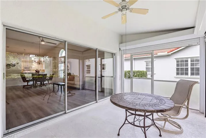 Screened patio with a ceiling fan, light-toned flooring, and roller shutters