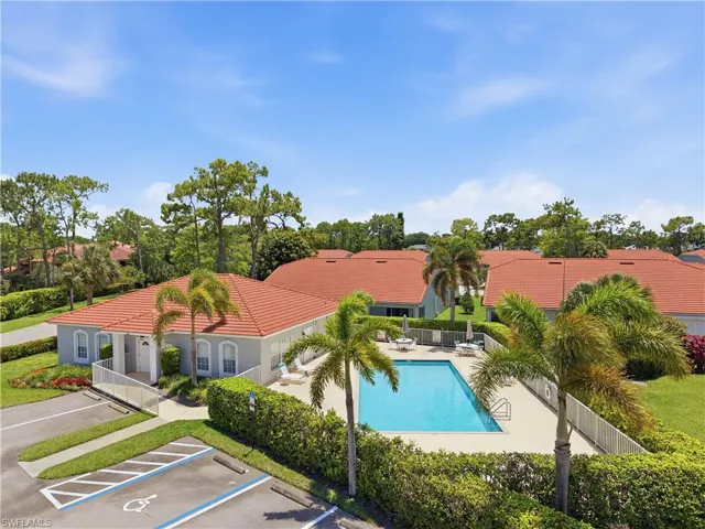 Community pool with surrounding patio space, lounge chairs, and umbrella-covered tables