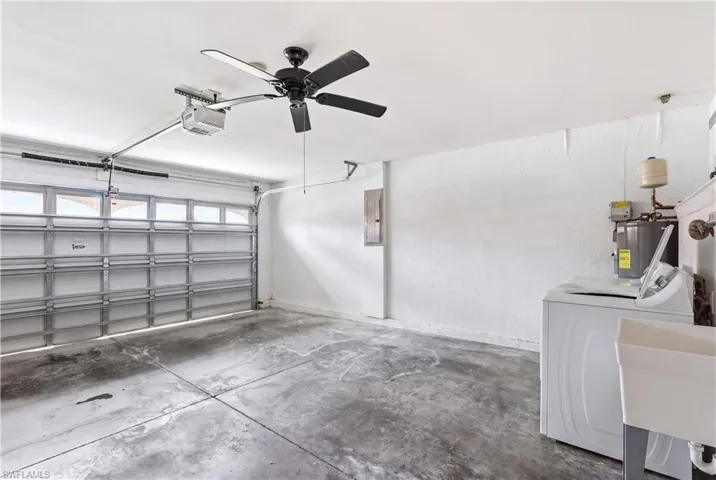 Attached garage featuring a rolling door with upper window panels, a ceiling fan, and concrete flooring