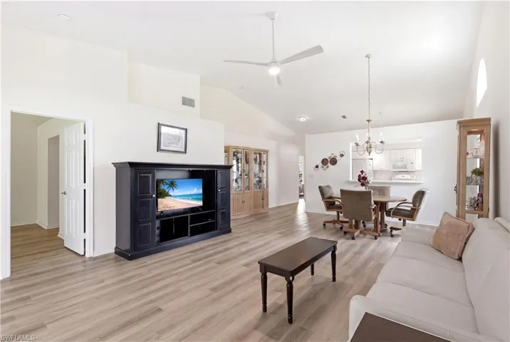 Spacious open-concept interior featuring light wood-finish flooring, vaulted ceilings, and a ceiling fan with integrated lighting