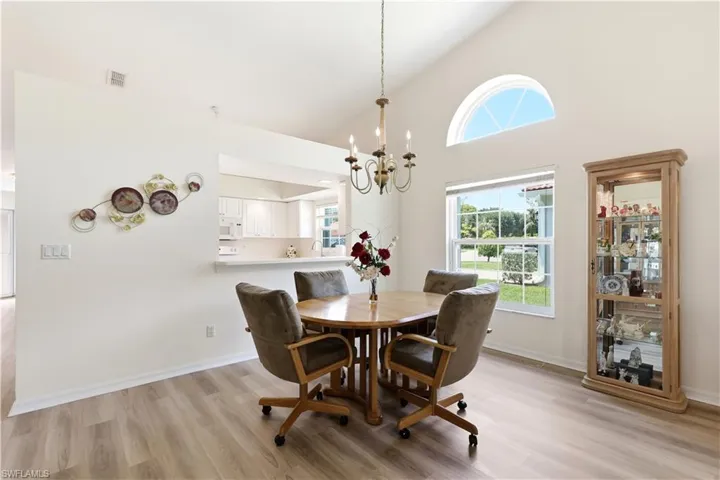Vaulted ceiling featuring a large arched window and a classic chandelier