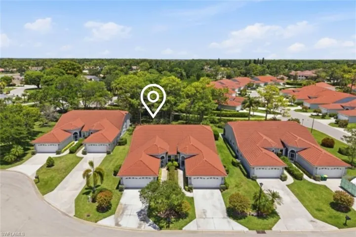 Aerial view of a residential community featuring multiple properties with terracotta tile roofs, attached garages, and manicured green lawns