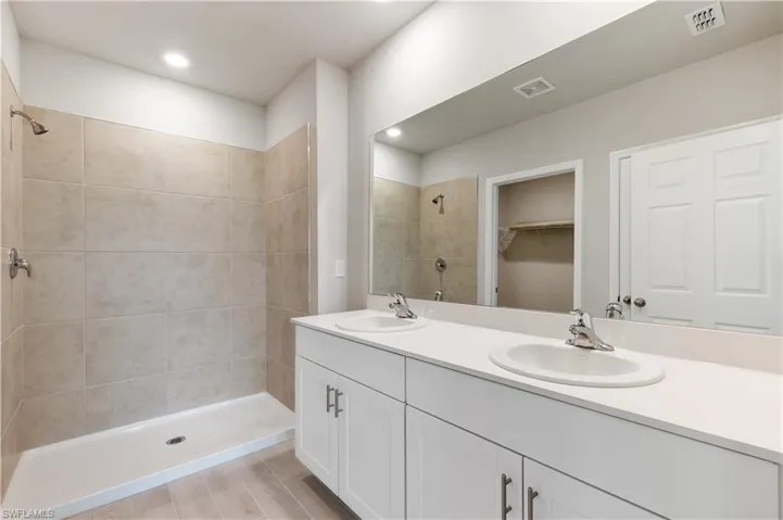 Bathroom with dual vanity and tiled shower
