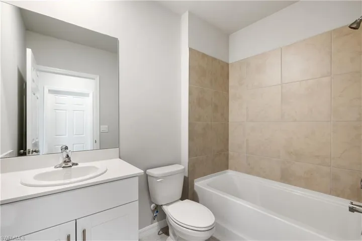 Full bathroom featuring vanity, tiled shower / bath combo, and toilet