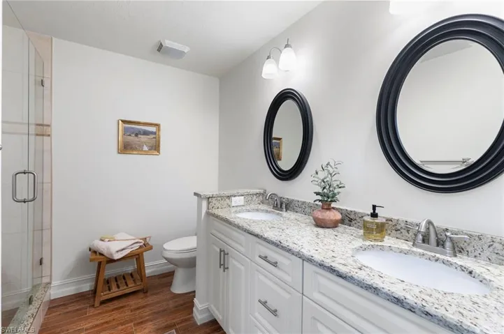 Bathroom with wood tiled floors, double vanity, and a stall shower