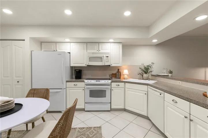 Kitchen featuring white cabinetry, white appliances, recessed lighting, and light tile patterned floors
