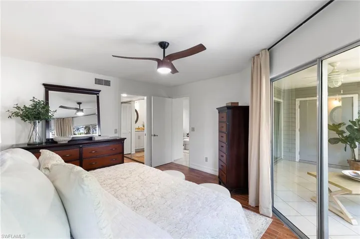Bedroom with light wood finished floors, a ceiling fan, and ensuite bath