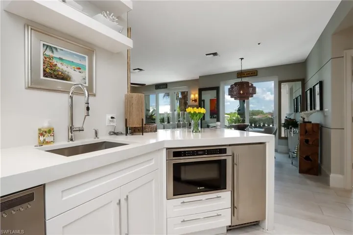 Kitchen with stainless steel appliances, light countertops, white cabinetry, a peninsula, and pendant lighting