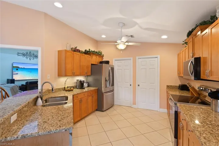 Kitchen with a peninsula, light stone countertops, appliances with stainless steel finishes, recessed lighting, and light tile patterned flooring