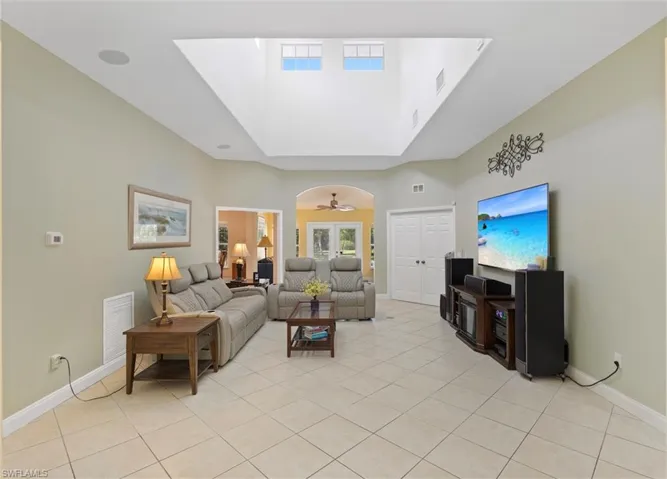 Living area featuring light tile patterned floors, ceiling fan, and a raised ceiling