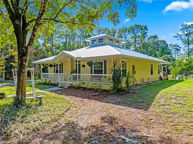 Country-style home featuring a porch, a metal roof, and a front lawn