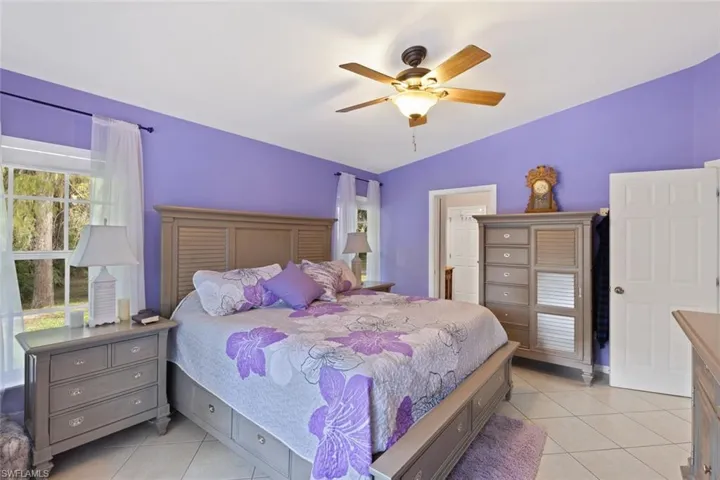 Bedroom with light tile patterned floors, lofted ceiling, and a ceiling fan