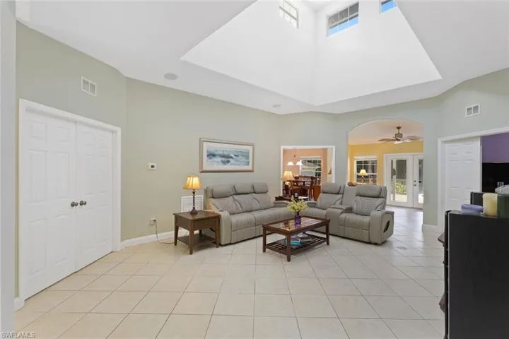 Living area with healthy amount of natural light, a towering ceiling, light tile patterned floors, and arched walkways