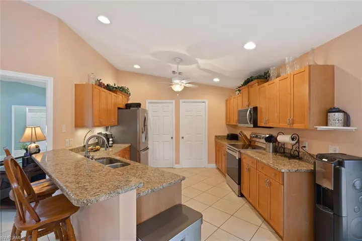 Kitchen with stainless steel appliances, light tile patterned floors, light stone countertops, recessed lighting, and a peninsula