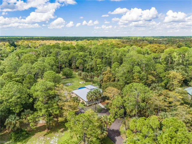 Aerial view of property and surrounding area featuring a forest