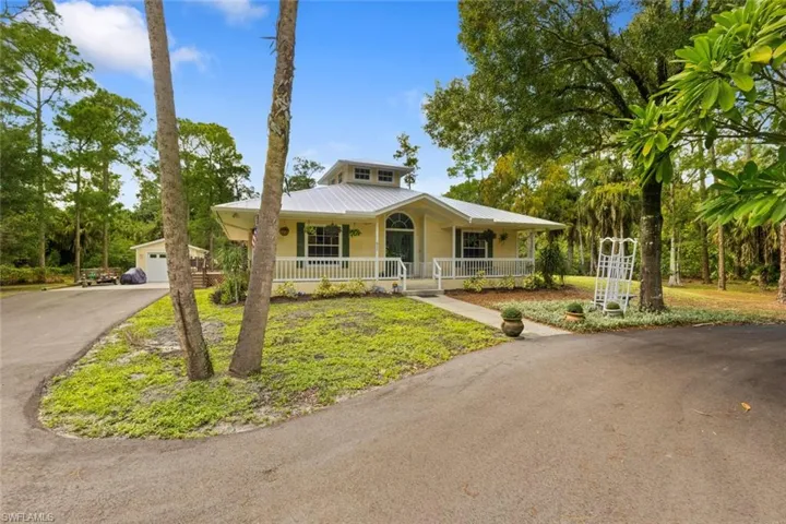 View of front of house featuring covered porch, a metal roof, a front lawn, and a garage
