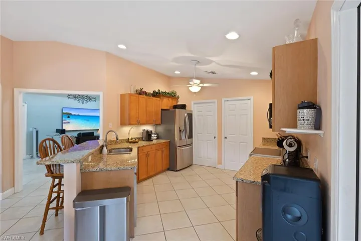 Kitchen featuring a peninsula, a kitchen breakfast bar, lofted ceiling, light stone countertops, and light tile patterned flooring