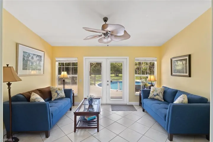 Living area featuring french doors, light tile patterned floors, and a ceiling fan