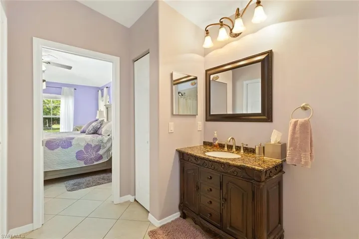 Full bath featuring vanity, light tile patterned flooring, and ensuite bathroom