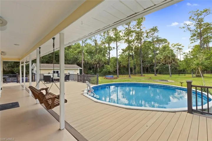 Outdoor pool featuring a patio, a wooden deck, and view of wooded area