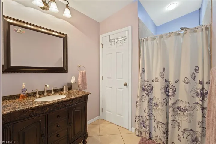 Bathroom with vanity, light tile patterned flooring, and a shower with curtain