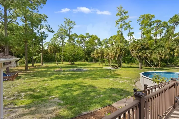 View of green lawn featuring an outdoor pool, a patio, and view of scattered trees