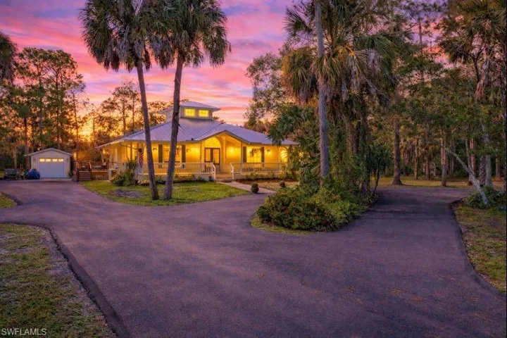 View of front of house with an outdoor structure, a garage, asphalt driveway, covered porch, and a metal roof
