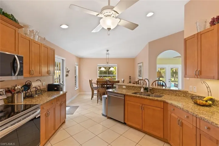 Kitchen featuring appliances with stainless steel finishes, brown cabinetry, recessed lighting, light stone countertops, and a peninsula
