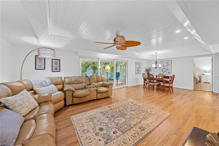 Living room featuring ceiling fan with notable chandelier and light wood-type flooring
