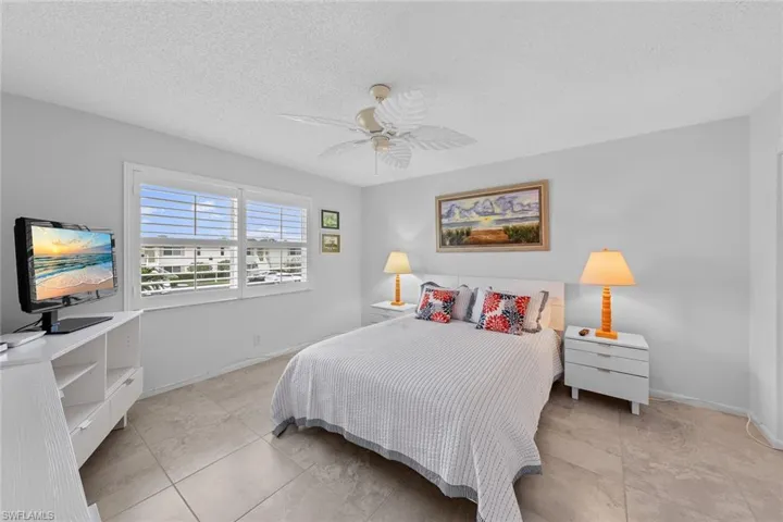 Tiled bedroom with ceiling fan and a textured ceiling
