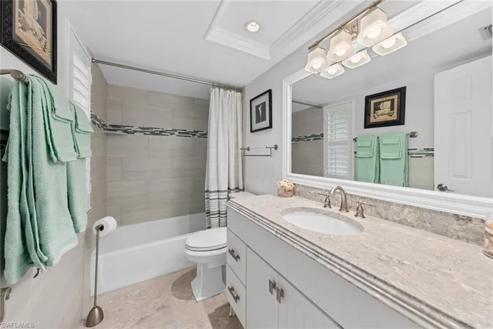 Full bathroom with toilet, vanity, shower / bath combination with curtain, and ornamental molding