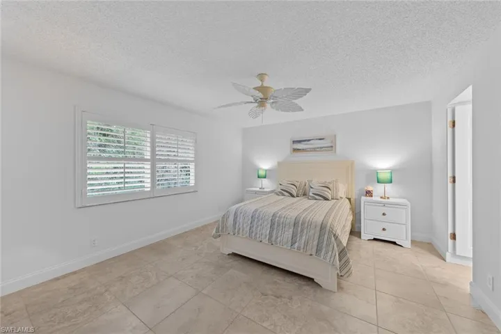 Bedroom featuring a textured ceiling, ceiling fan, and light tile patterned flooring
