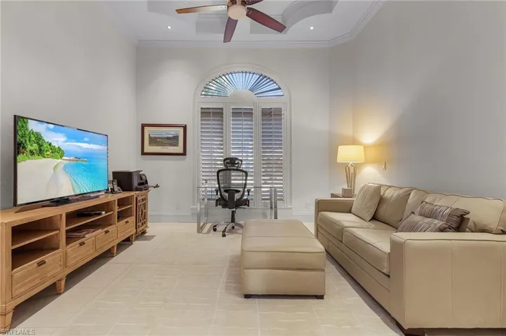 Tiled living room with crown molding, a towering ceiling, and ceiling fan