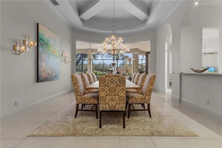 Tiled dining area with a towering ceiling, beam ceiling, ornamental molding, coffered ceiling, and an inviting chandelier