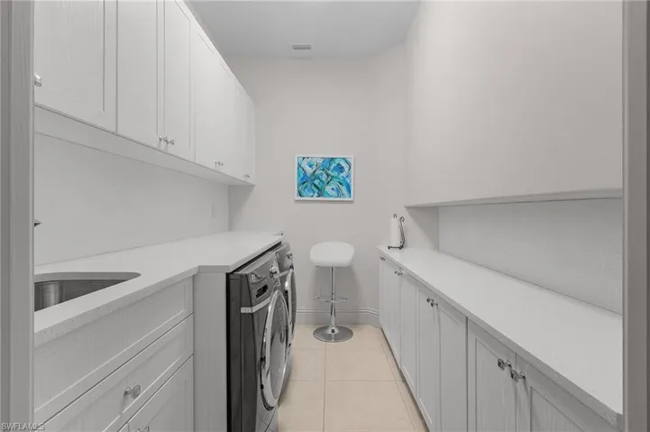 Laundry room featuring light tile patterned flooring, sink, cabinets, and washer and dryer
